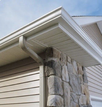 White gutter and downspout along a stone and siding exterior