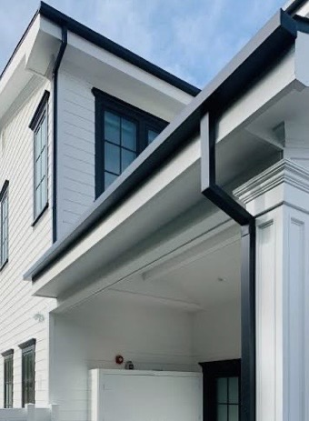 Black seamless gutters and downspout on a modern white home